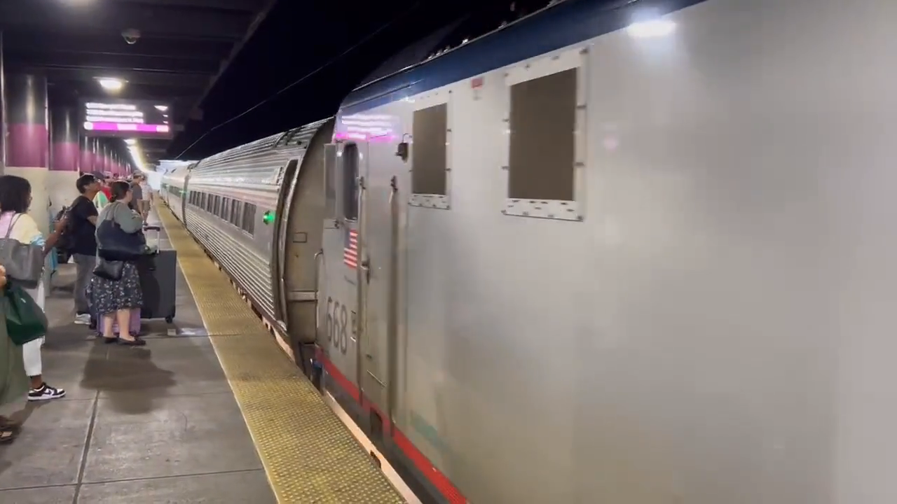 A frame from Elorian’s train example, with a passing train beside people on the platform.